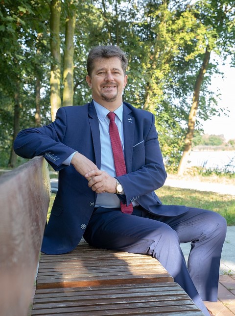 Burmistrz Marek Charzewski siedzący na ławce w parku miejskim