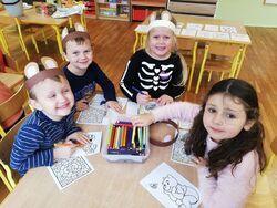 Na zdjęciu widać czwórkę przedszkolaków przy stole z rysunkami