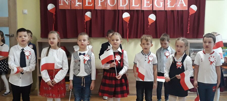 na zdjęciu widać dzieci z flagą Polski i napisem w tle "Polska Niepodległa"